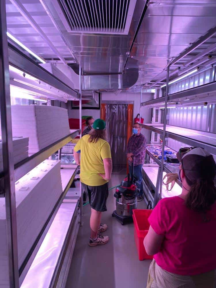 A group of people in a hydroponic container farm. End of image description.