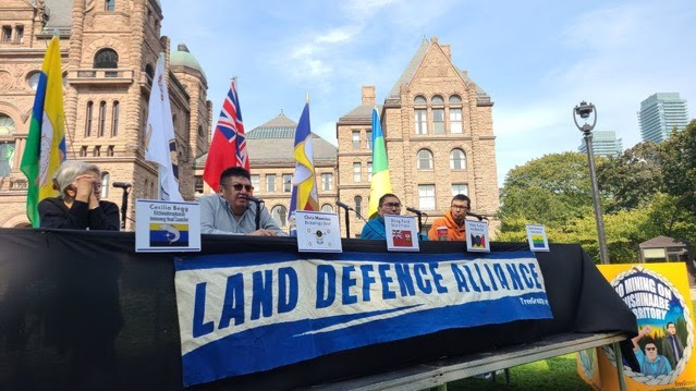 A panel of Indigenous leaders and a banner that says "Land Defence Alliance". End of image description.