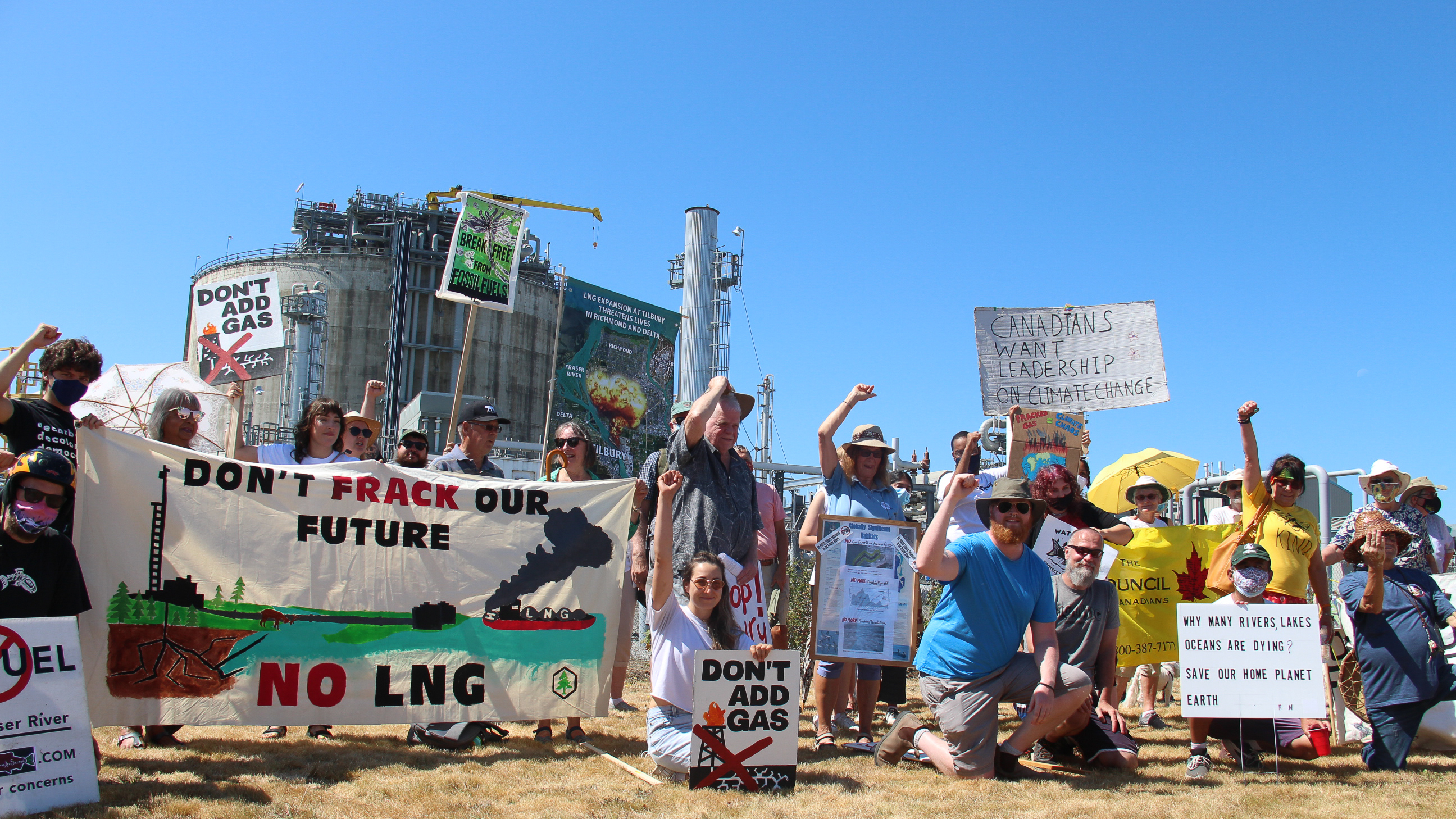 People protesting outside Tilbury LNG facility in Delta, BC. Their signs say "Don't frack our future, NO LNG" and "Don't add gas".