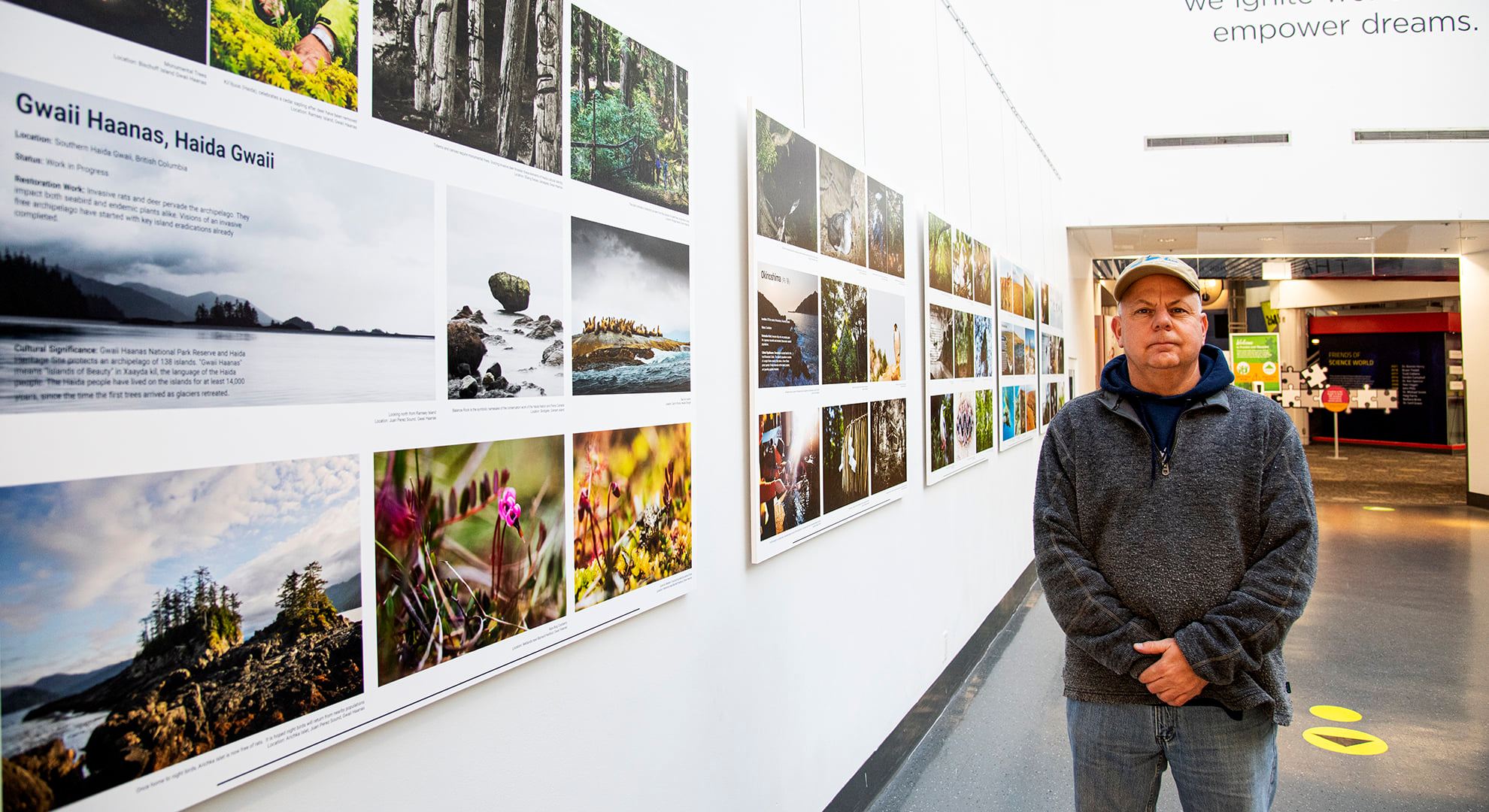 Photographer Andrew Wright with a gallery wall of his conservation images.