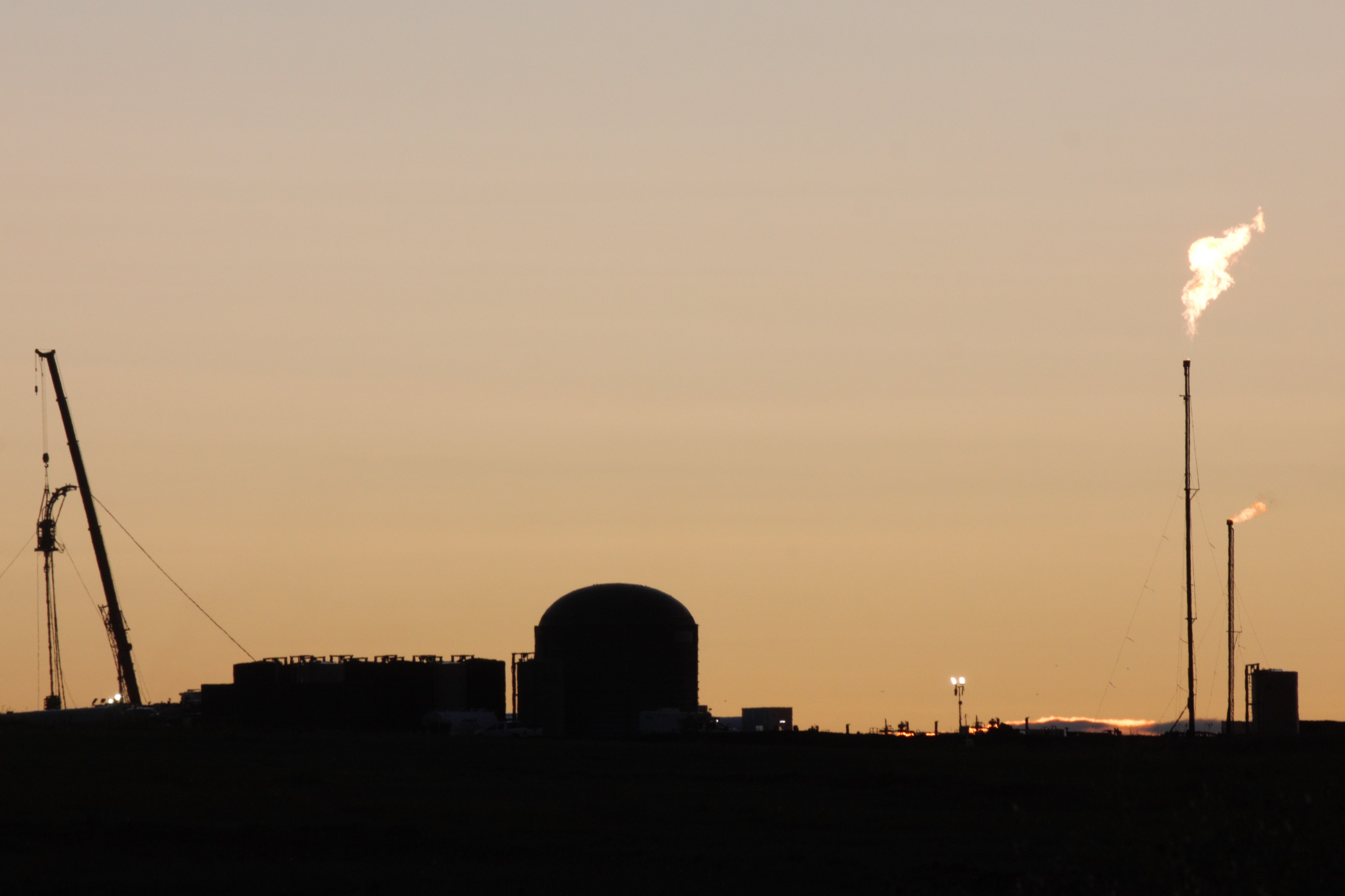 Skyline of a fracking plant with its flare stack burning away.