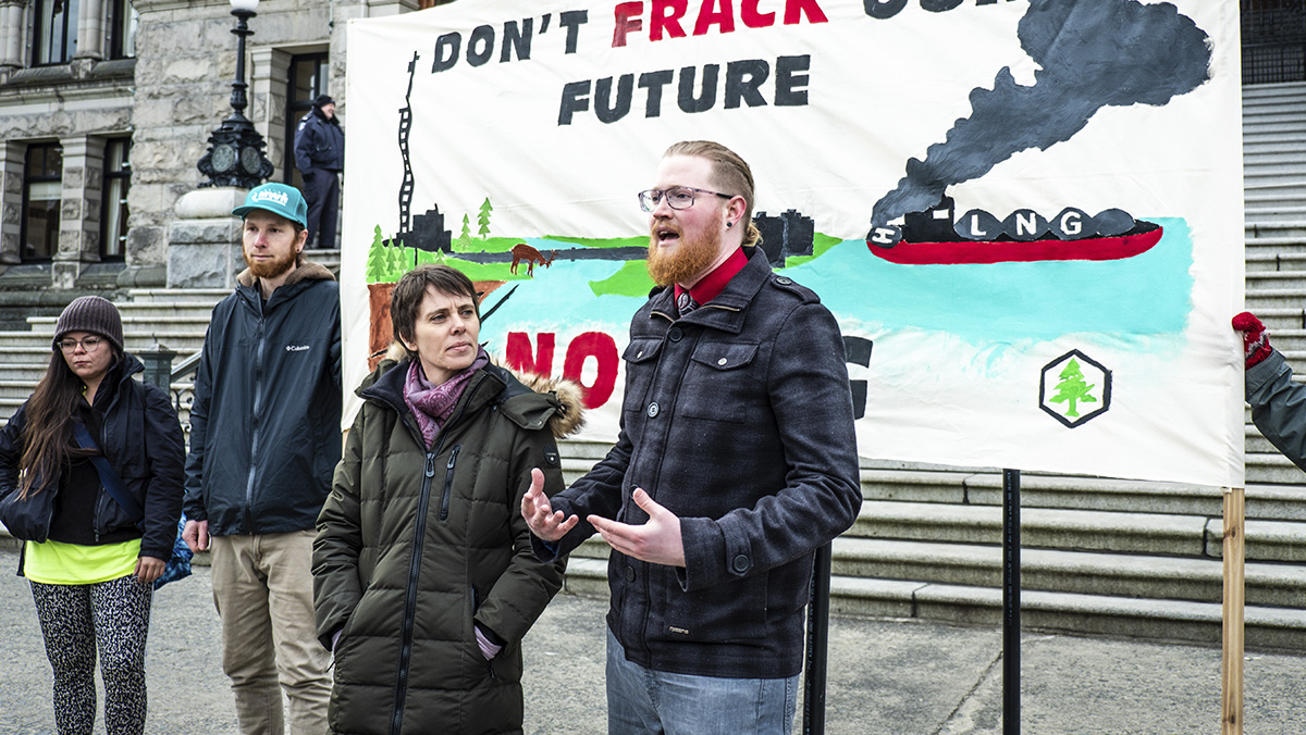 Climate Campaigner Peter McCartney standing on the front steps of the Legislature in Victoria handing in a petition to stop LNG