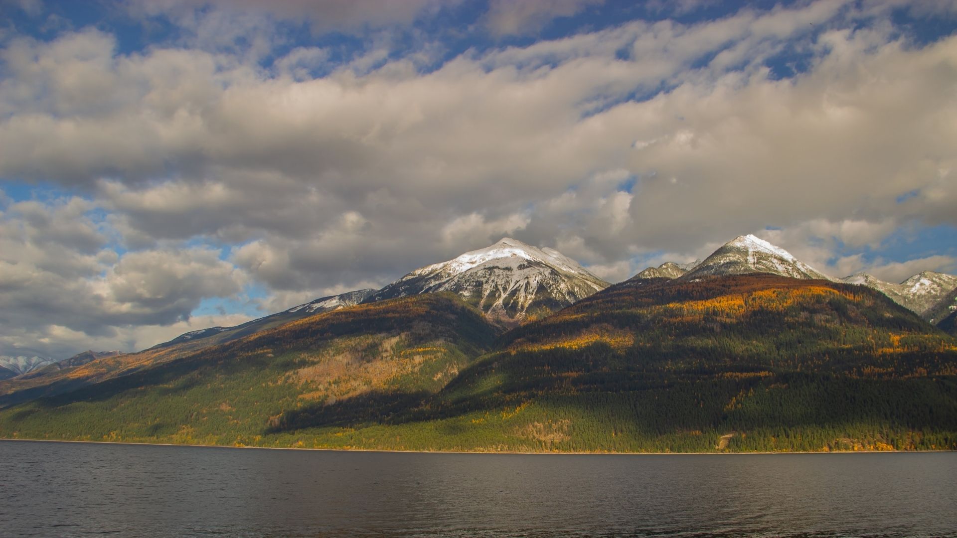 Two mountains across an ocean, with clouds in the sky. End of image description.