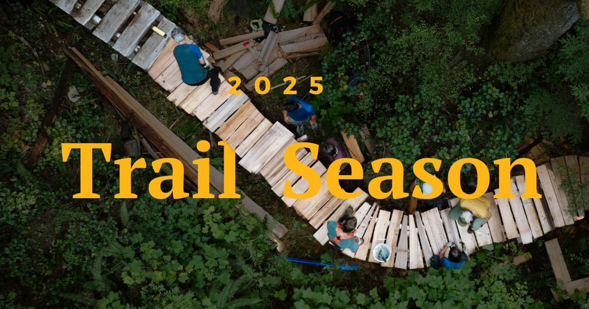 An aerial shot of people working on a wooden trail in the middle of the forest. Text on the image says "2025 Trail Season."