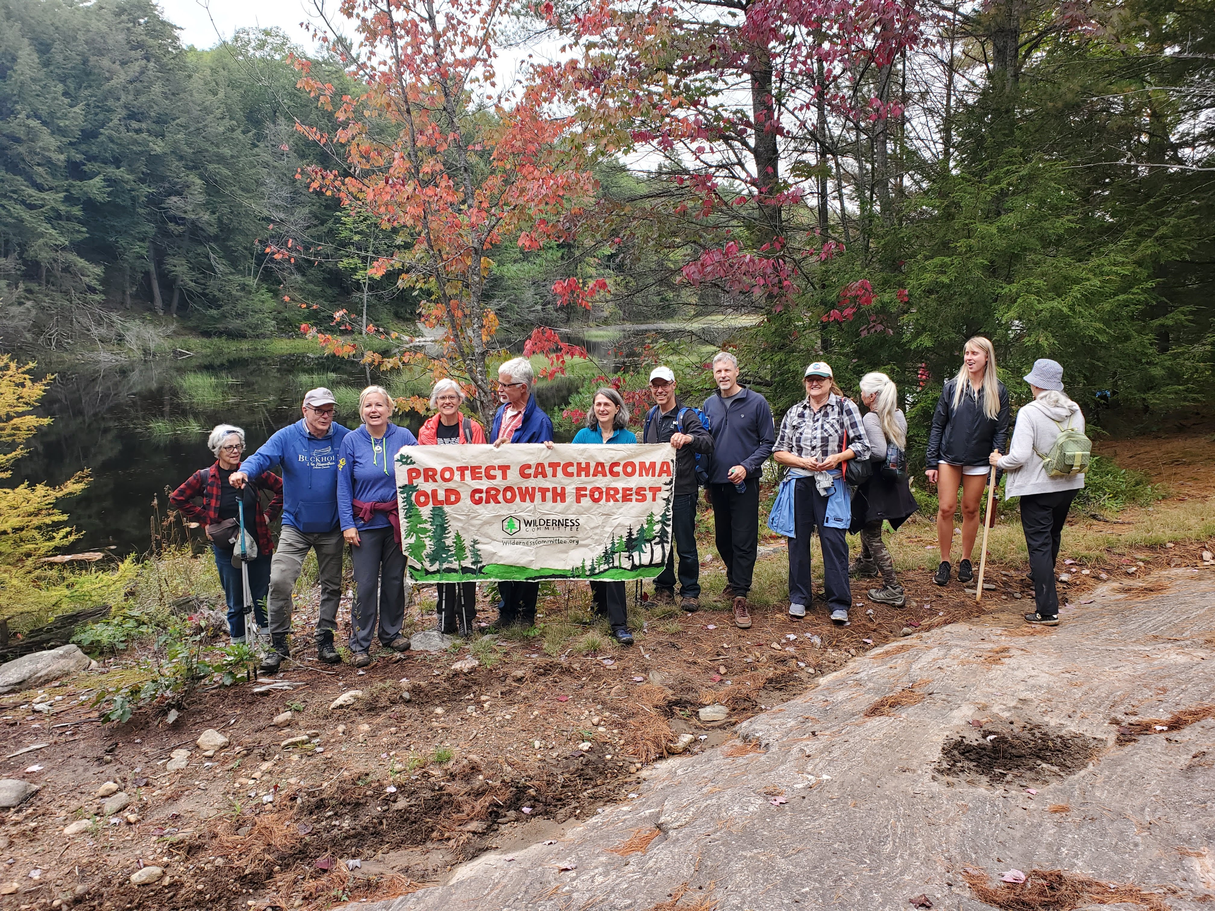 Group of hikers in Catchacoma old-growth forest holding Wilderness Committee sign to protect the forest.