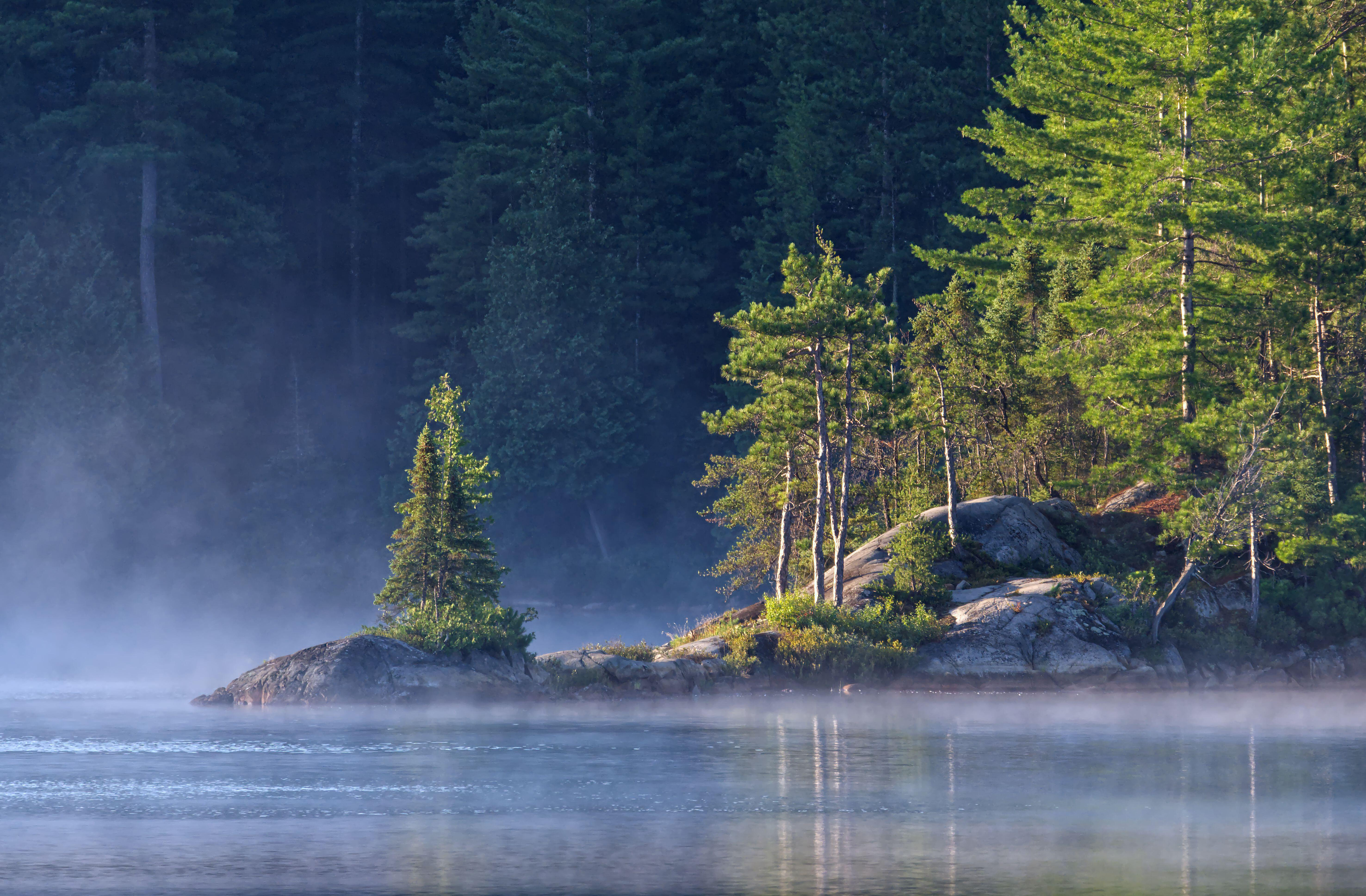 An intimate landscape image taken as the sun rises by a rocky point on Wolf Lake in Temagami, Ontario.