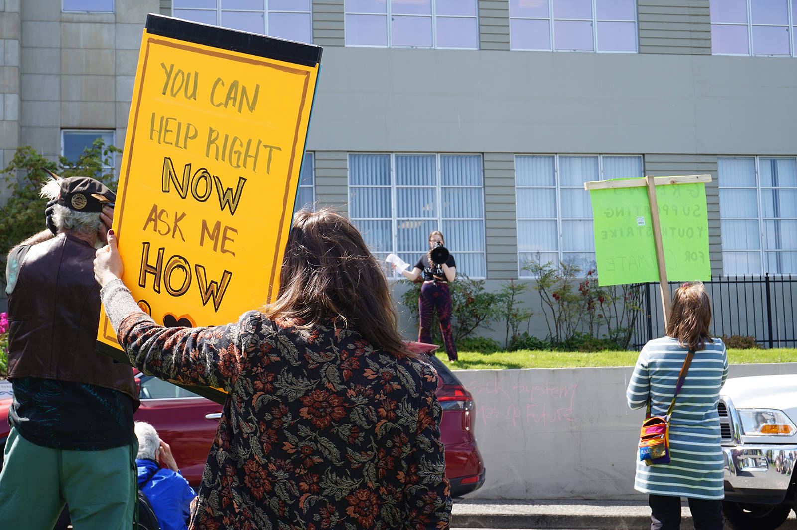 Protestors hold signs while Allison Walters speaks.