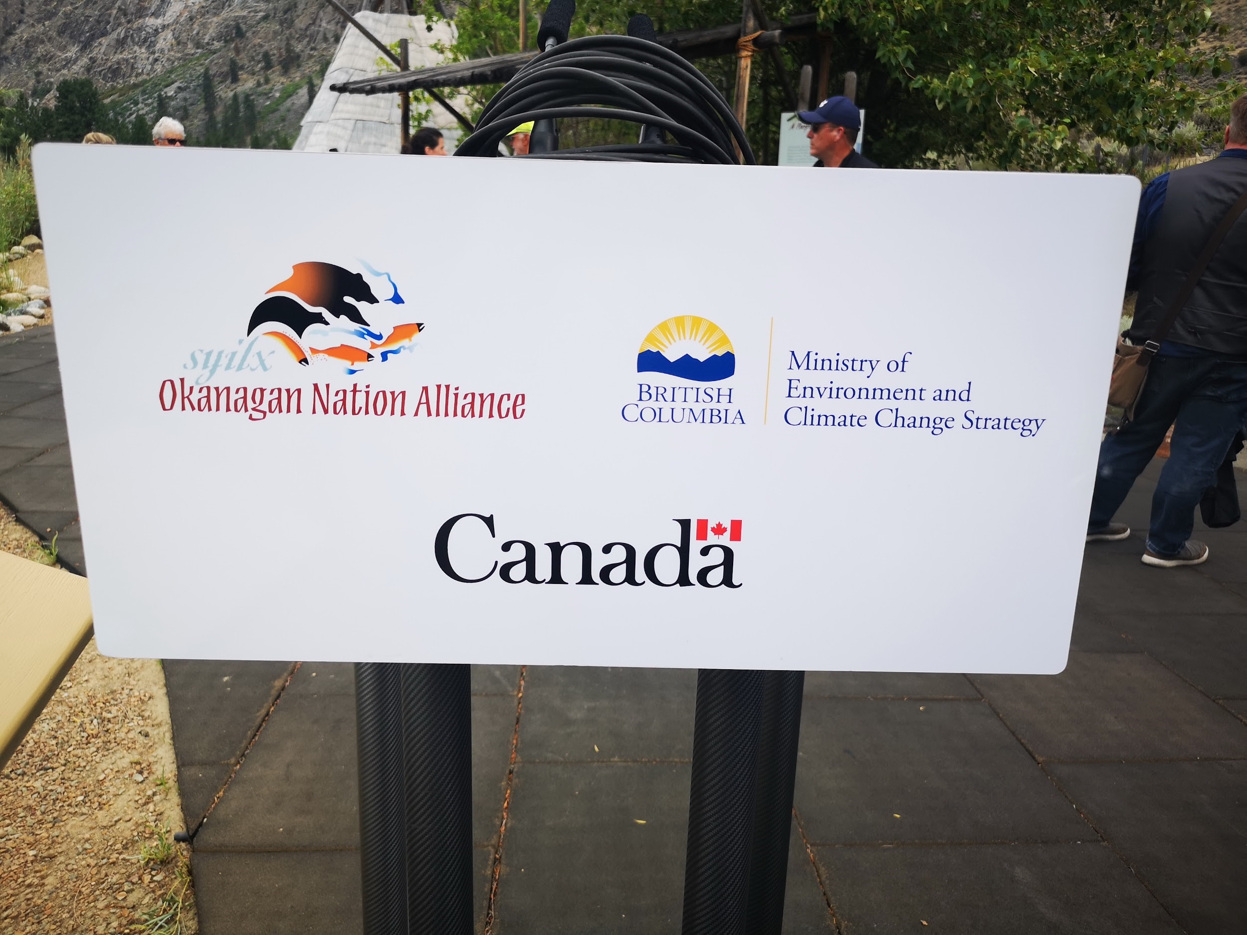 a podium with the logos of Syilx/Okanagan Nation Alliance, BC and Canada