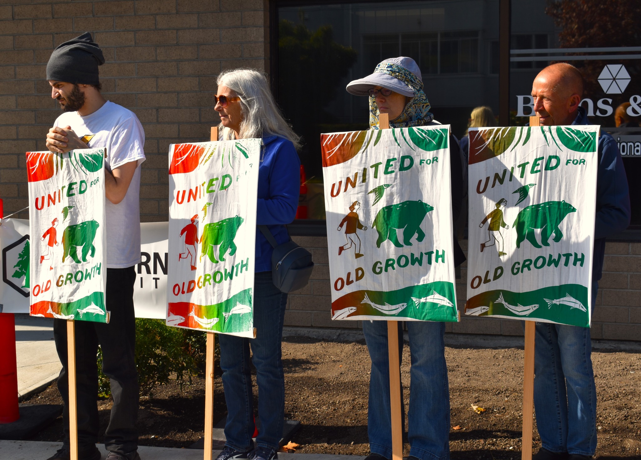 A group of people holding up signs in support of old-growth trees. End of image description.