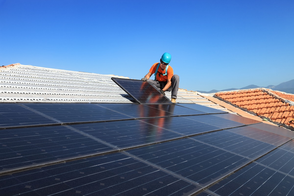 Worker installs solar panels on roof. End of image description.
