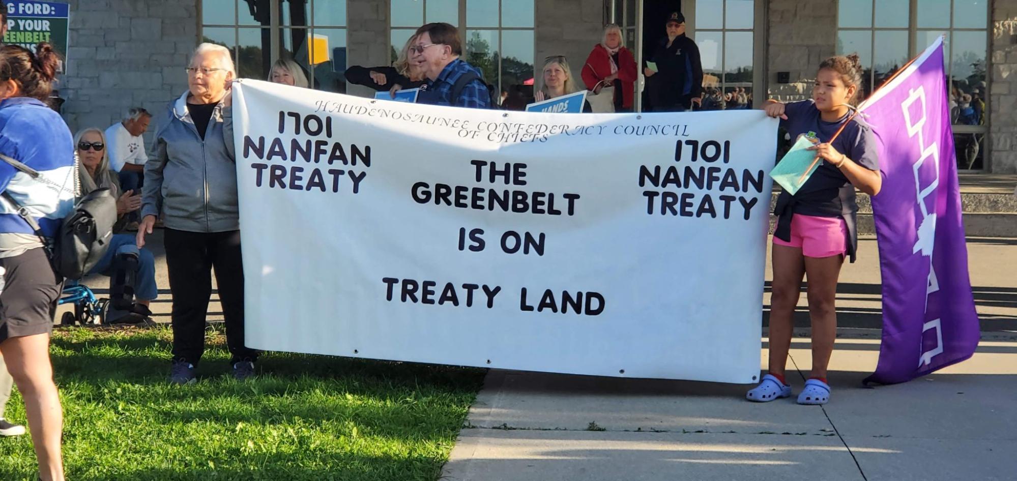A group of Indigenous people holding up a banner that says "The Greenbelt is on Treaty Land, Nanfan Treaty." End of image description.