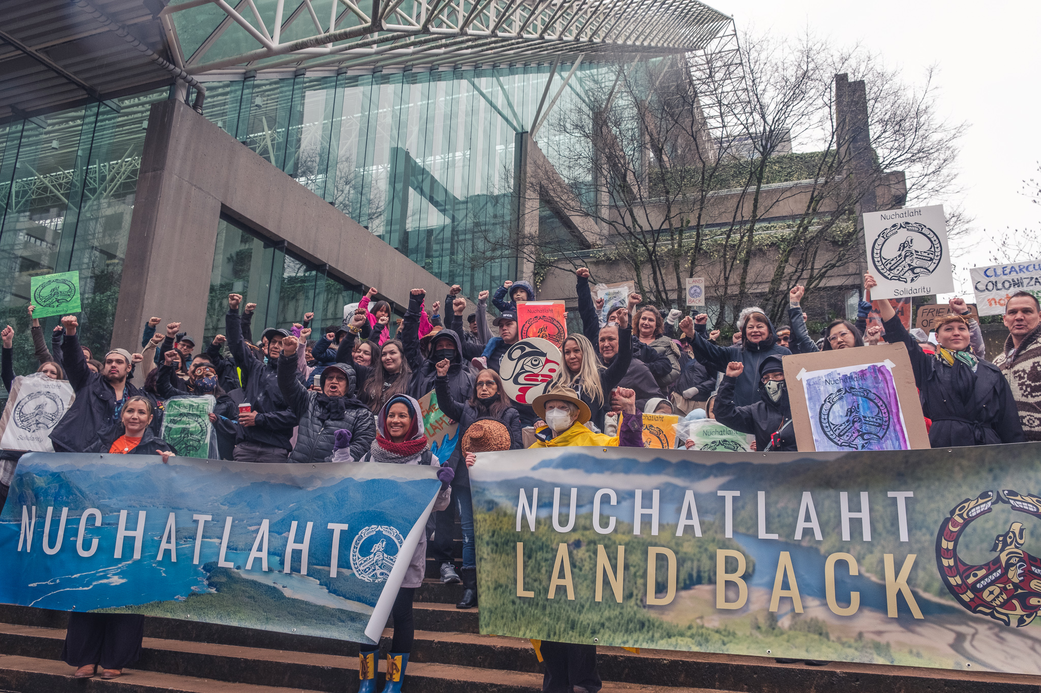 A group of people standing and holding up signs in support of Nuchatlaht. End of image description.