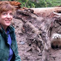 Gwen Barlee smiling next to a badger in its den.