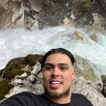 A photo of Cedar posing over a waterfall. End of image description.