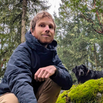 A photo Michael in an old-growth forest with his dog.