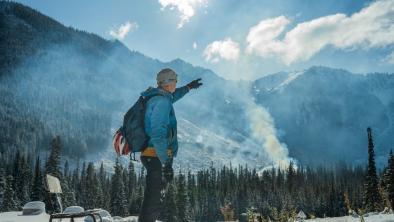 Paul Berntsen stands at the foundation of his yurt, from which he hoped to operate a non-motorized eco-tourism company before his permits were denied. The Silverdaisy peak in Manning Park and a recent clear cut are obscured by smoke from ongoing burning of waste wood. Photo: Fernando Lessa / The Narwhal