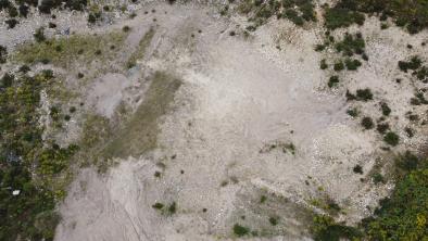 Aerial view of a gravel pit with sparse vegetation at its edges.