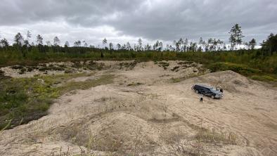 A gravel pit stretches between distant edges of forest.