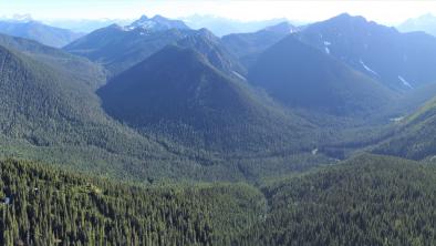 Wide panorama of forested mountains surrounding a small valley.