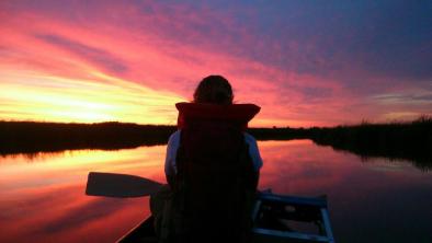 Canoe in sunset. End of image description