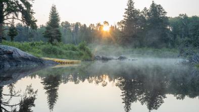 A yellow canoe sits on the lower Bird River during a foggy sunrise