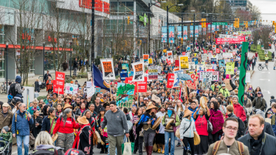 A group of people marching down the street, protesting Kinder Morgan and the Trans Mountain pipeline. End of image description.