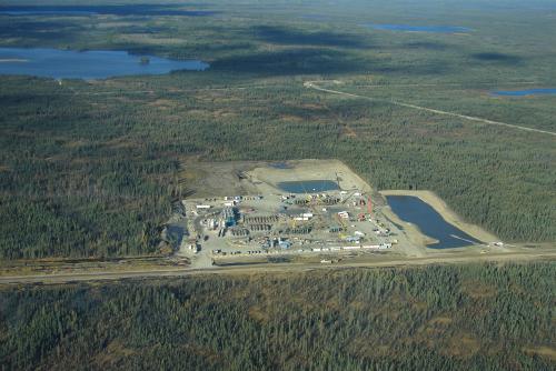Aerial view of a fracking pad and infrastructure surrounded by forest, with a road through it
