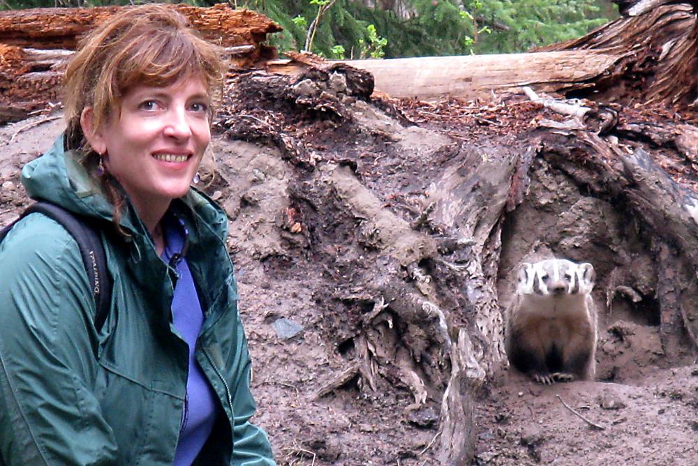 Gwen Barlee smiling next to a badger in its den.
