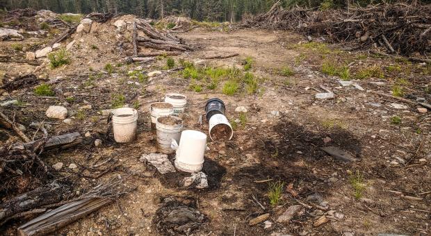 Pails of dirty oil spill onto contaminated ground in Nopiming Provincial Park, violating the law.