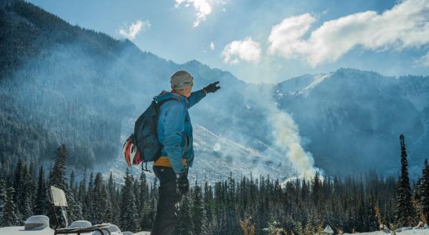 Paul Berntsen stands at the foundation of his yurt, from which he hoped to operate a non-motorized eco-tourism company before his permits were denied. The Silverdaisy peak in Manning Park and a recent clear cut are obscured by smoke from ongoing burning of waste wood. Photo: Fernando Lessa / The Narwhal