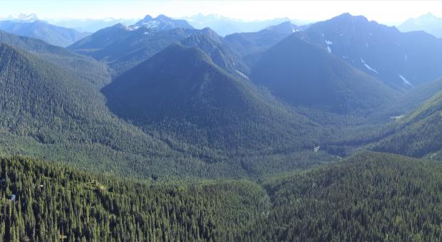 Wide panorama of forested mountains surrounding a small valley.