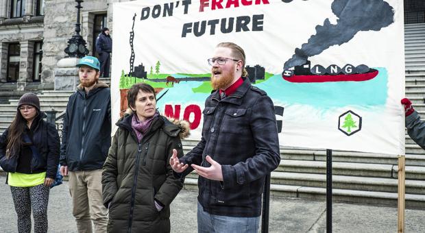 Climate Campaigner Peter McCartney standing on the front steps of the Legislature in Victoria handing in a petition to stop LNG