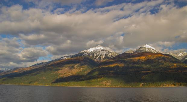 Two mountains across an ocean, with clouds in the sky. End of image description.