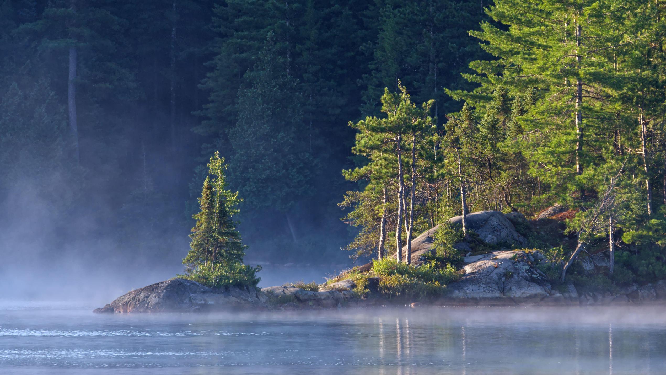 An intimate landscape image taken as the sun rises by a rocky point on Wolf Lake in Temagami, Ontario.