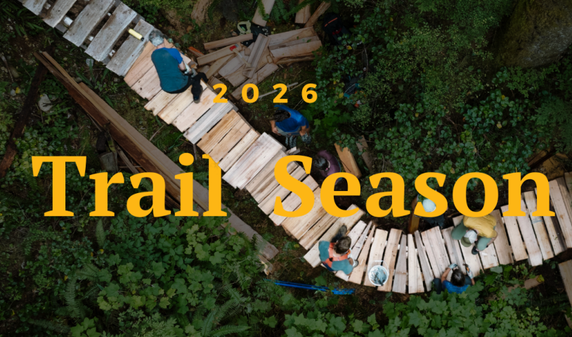 An aerial shot of people working on a wooden trail in the middle of the forest. Text on the image says "2026 Trail Season." 