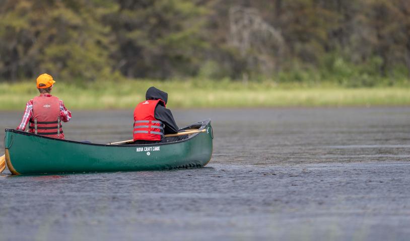 Two canoers paddling down springer lake in Manitoba. End of description.