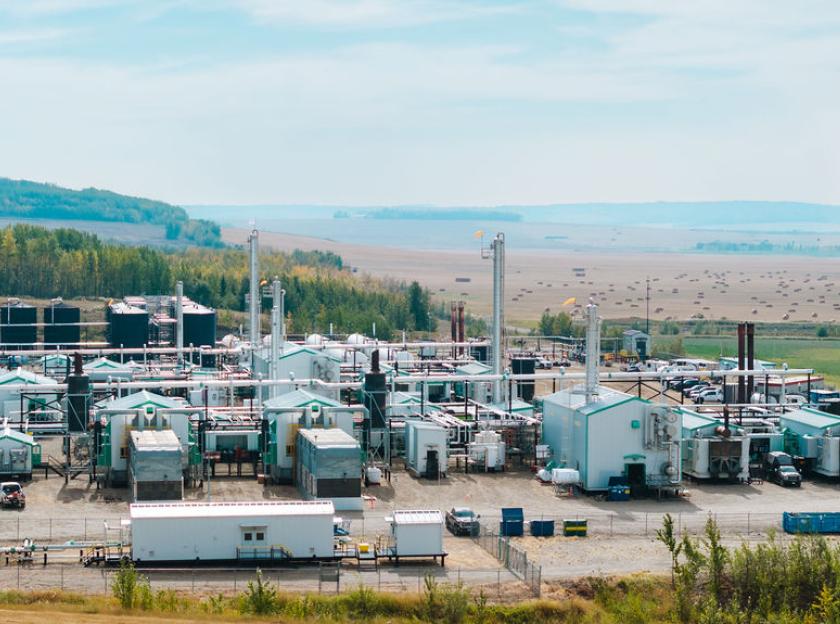 Fracking infrastructure in North Eastern BC against a background of hills, trees and agricultural land