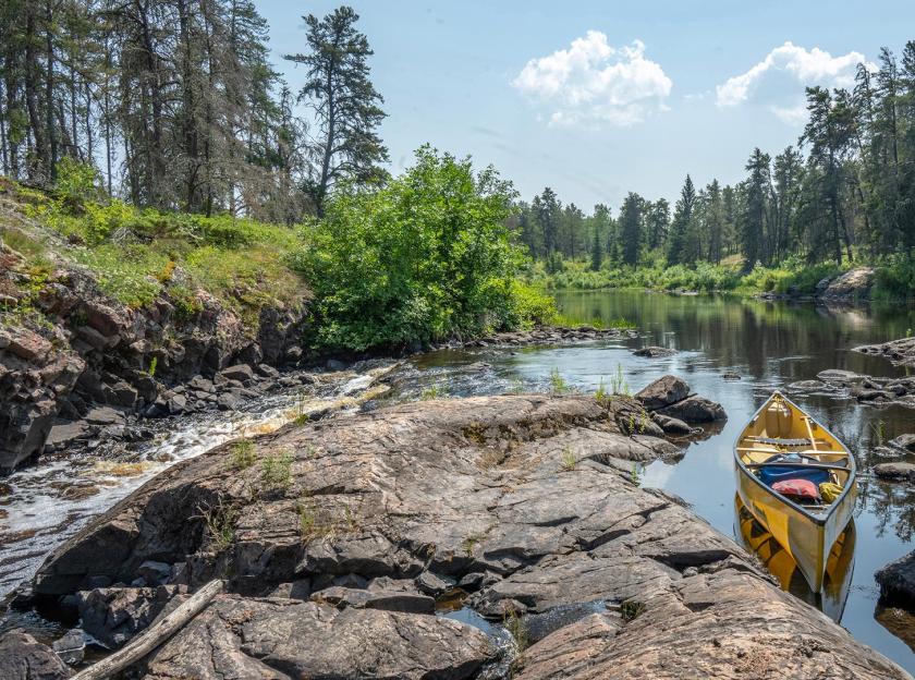 Canoe sitting on rice river, trees and blue sky in the background